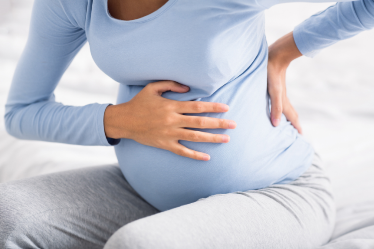 woman with a babybelly grabbing her back